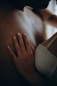 a couple up close and personal in a hug. The man is shirtless. The woman has her hands on his chest.