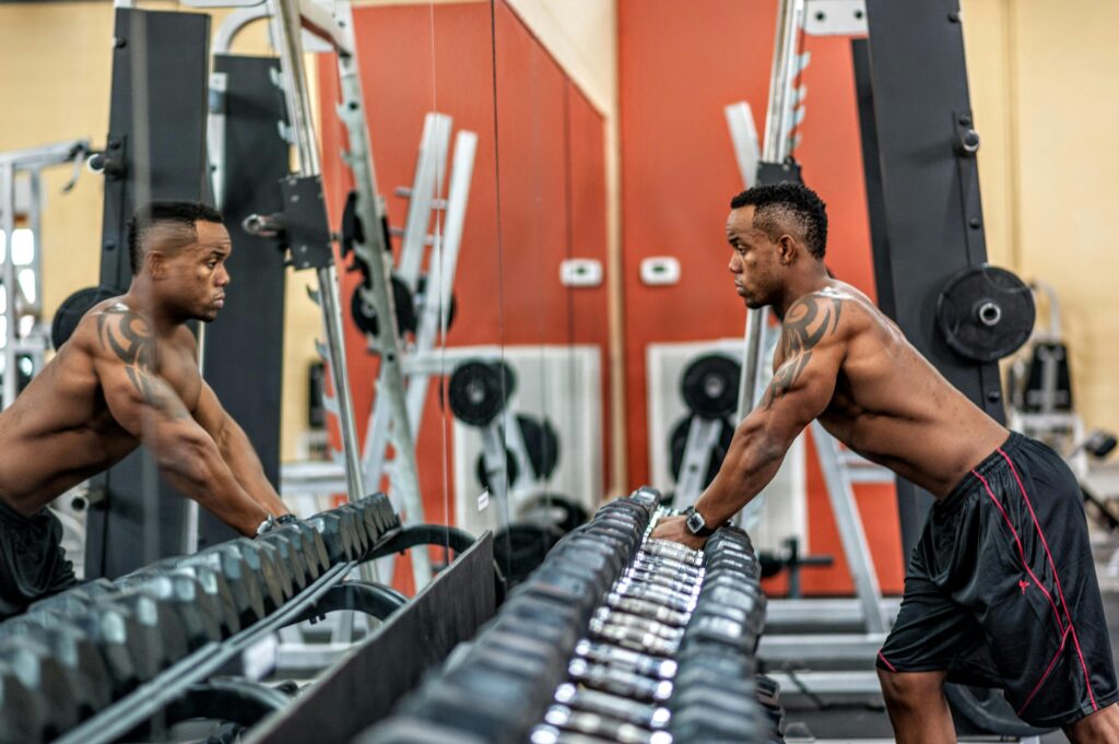 Tighten skin by strength training- a man stands at the dumbbell section of the gym preparing to lift weights