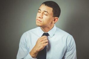 Positive Motivational Quotes for when your patience runs thin are needed quick, fast, and in a hurry. This is a picture of man with a look of frustration on his face as he shifts his tie with a frustrated look on his face, eyes closed as if looking for peace and restraining from his real feelings of annoyance