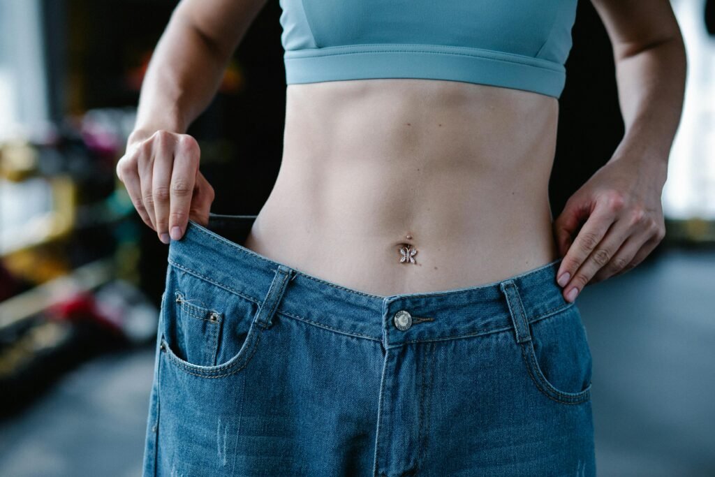 How to Lose Belly Fat After 30 - an image of a woman pulling her once large pants away from her midsection indicating how much belly fat she's lost