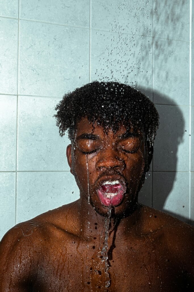 morning routine to speed up metabolism - a man is taking a shower. He has his eyes closed and his mouth open.