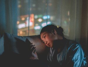 why toxic relationships are addictive - a woman stares at her lit cell phone in the dark as if sending text messages