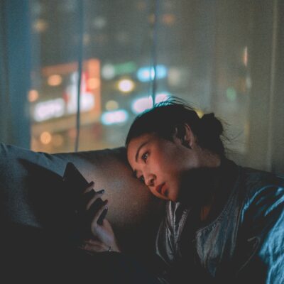 why toxic relationships are addictive - a woman stares at her lit cell phone in the dark as if sending text messages