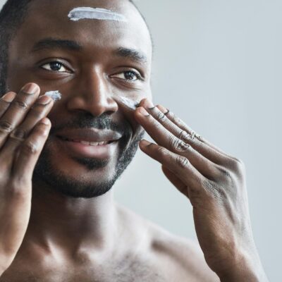 best restorative face cream - a man moisturizes his skin while looking in a mirror