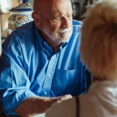 What Morning Habits Increase Dementia? an image of an elderly man who looks bothered by his thoughts as his partner sits across from him