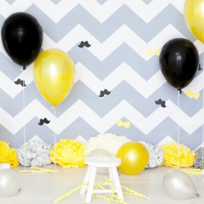 how to be your own cheerleader - an empty stool with pompoms and balloons in the chevron gray & white background