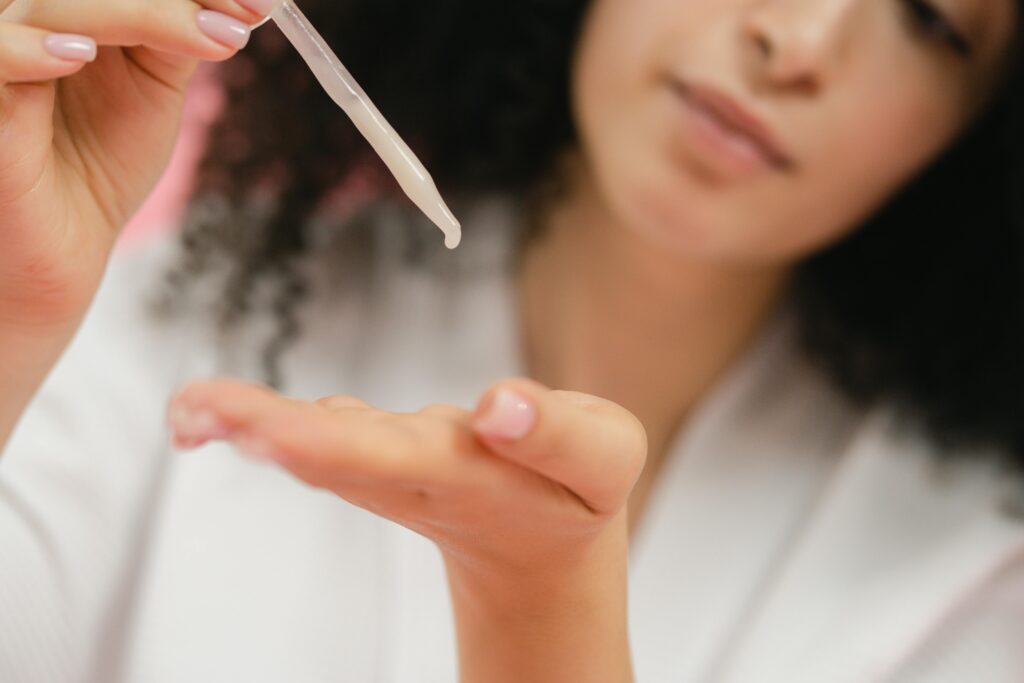 mature skin serums for women - a woman places a dropper of serum in the palm of her hand