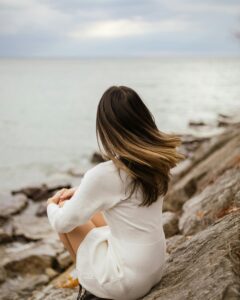 the back of a woman's head as she sits on the sea shore