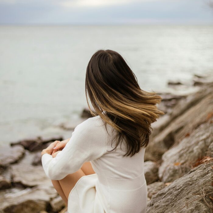 the back of a woman's head as she sits on the sea shore