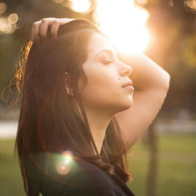 protect your peace - a woman stands in solitude with eyes closed as the sun shines over her