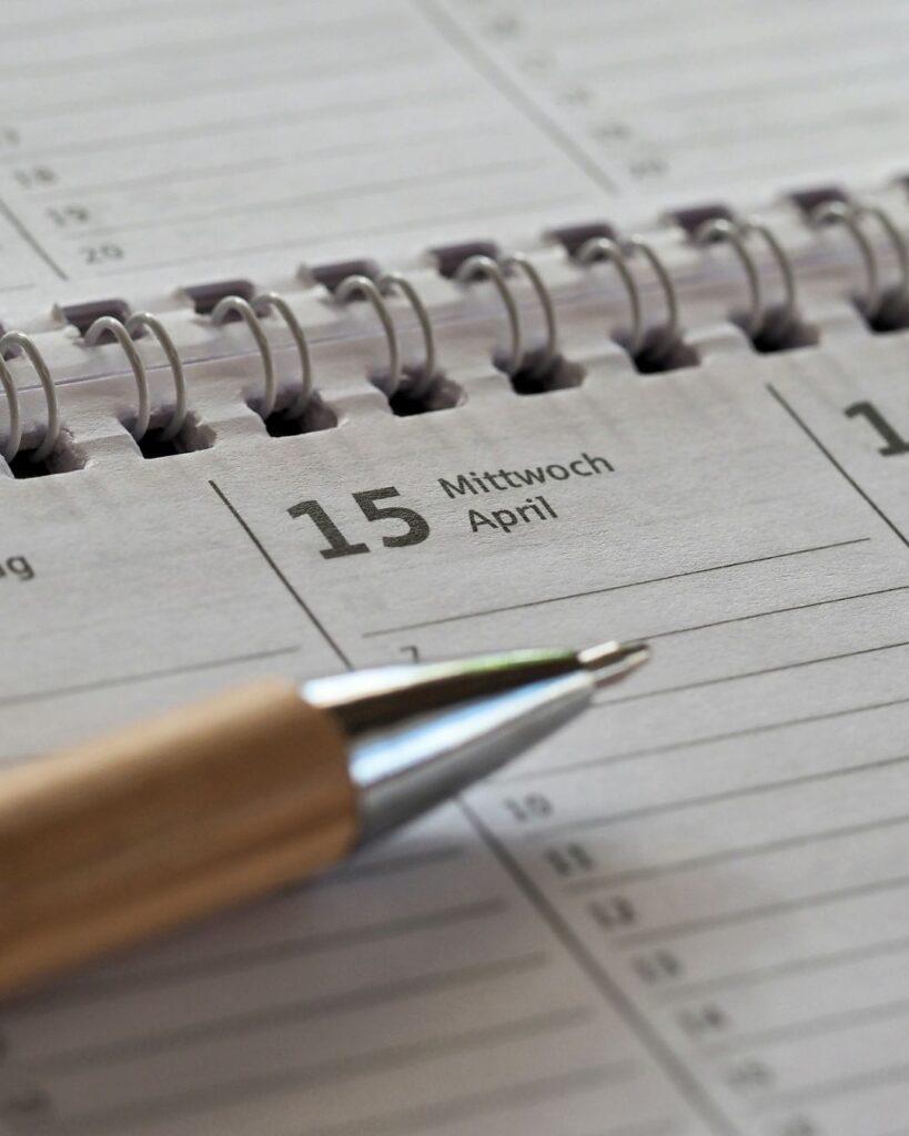 Close-up of a spiral-bound planner open to April 15 with a pen resting on the page, representing scheduling, planning, and organizing daily priorities.