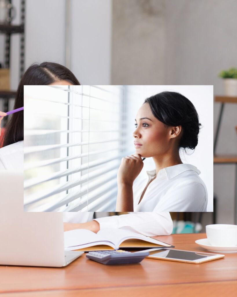 Woman sitting at a desk with a laptop, notebook, calculator, and coffee while thoughtfully looking out a window, representing reflection, planning, and getting life organized.