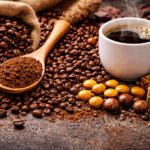 High-resolution image of caffeine sources including roasted coffee beans spilling from a burlap sack, a wooden spoon filled with ground coffee, a steaming cup of black coffee, dark chocolate pieces, and sugar cubes arranged on a textured surface.